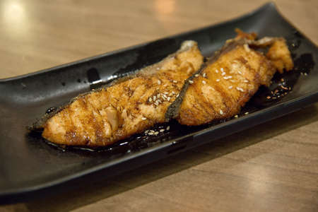 Crispy salmon and soy sauce in a black plate, in focus selective.の写真素材