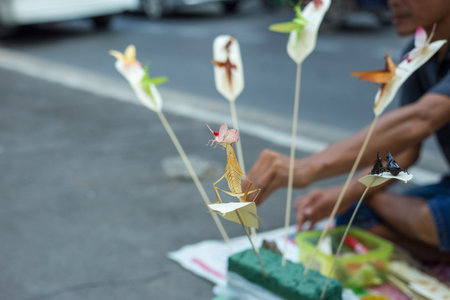 Bangkok, THAILAND - February 9, 2019: People who make handcraft, folding colourful fake insects make with palm leafed at wayside for sale to tourist.のeditorial素材
