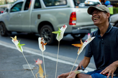 Bangkok, THAILAND - February 9, 2019: People who make handcraft, folding colourful fake insects make with palm leafed at wayside for sale to tourist.のeditorial素材