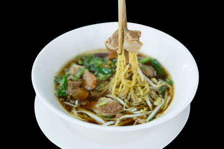 Soup Stewed beef noodles pick up with chopsticks on black isolated.