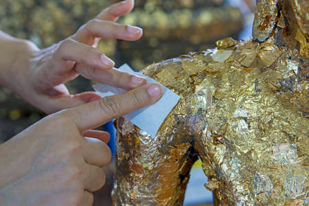Hand of people or buddhist gild by gold leaf on brass buddhaの写真素材