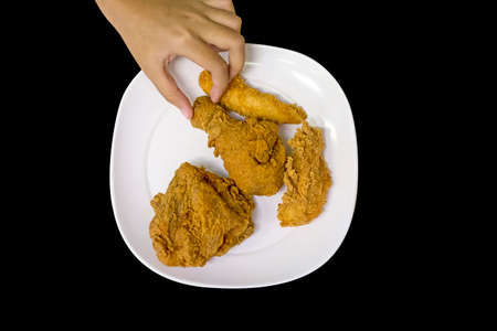 hand pickup a piece of fried chicken black pepper die cut on black background.の写真素材