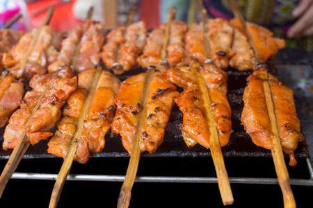 Skewer Raw chicken pieces roasting on the grill and smokeの写真素材