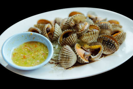 Parboiled fresh cockles in the dish scald cockles with seafood sauce, die cut black isolated, focus...