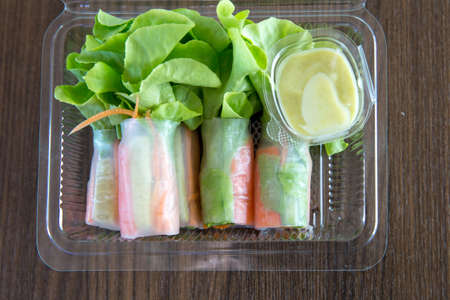 Spring rolls with vegetables and rice paper, Green Oak Lettuce in transparent plastic package, on...