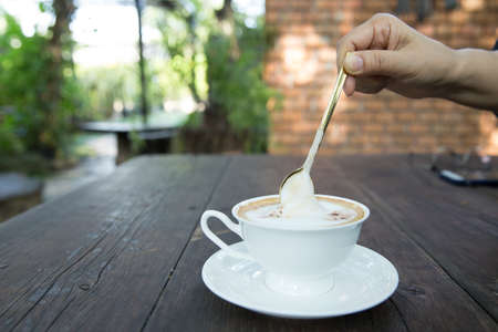 Closeup of female hands with a mug of coffee beverage, focus selective.の写真素材