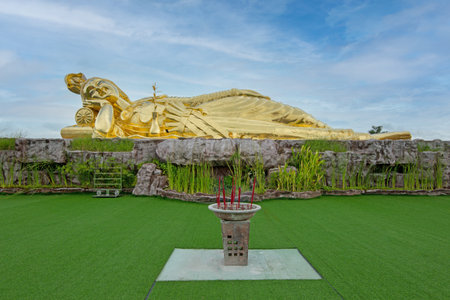 Nakhon Pathom / Thailand - July 25 2020: Guanyin Golden statue of a lying on blue sky background, Artificial grass in front in Wat Tram Panyaram, very famous for tourist in Nakhon Pathom province.のeditorial素材