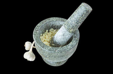 Many of pound garlic in Black stone mortar and pestle, focus selective.の写真素材