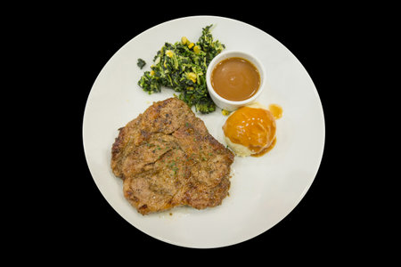 Die cut of grilled pork chop with knife and fork, on black isolated.の写真素材