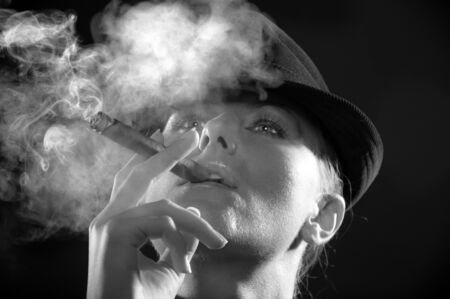 Backlight image of girl in the hat smoking cigarの写真素材