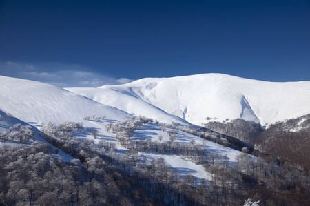 Snow-covered high mountains of Alp in winter against the blue sky
