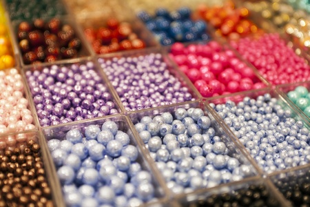 multi-colored beads in a box on a shelf in the marketの写真素材