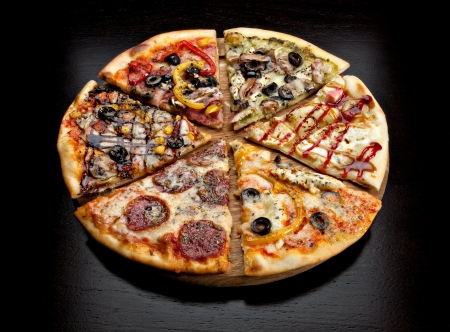 six slices of pizza with different toppings on a wooden board on black backgroundの写真素材