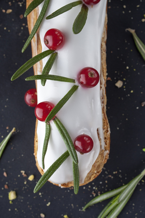 exquisite cream dessert eclair with redcurrant and fresh rosemary leaves