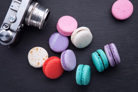 delicious French dessert macarons with vintage camera on a black background