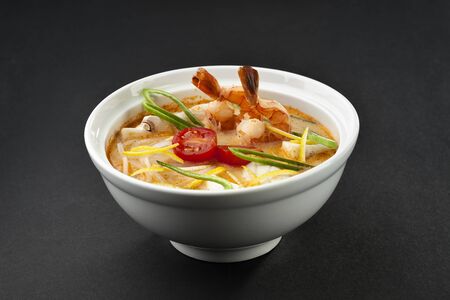 Appetizing soup with seafood in a white plate on a black backgroundの写真素材