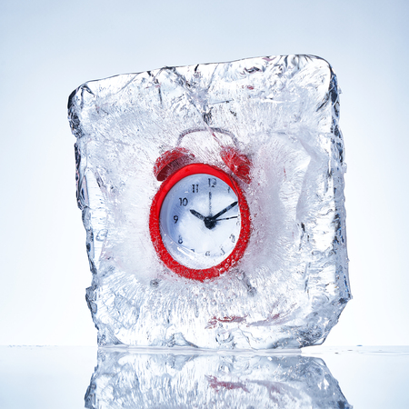 Red alarm clock in a piece of iceの写真素材