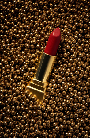 A classic red lipstick in a gold case on a gold non-standard backgroundの写真素材