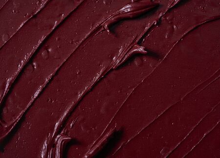 Smear of burgundy red lipstick or acrylic paint isolated on white background