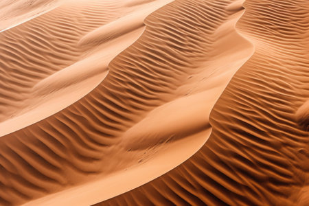 This captivating image showcases the abstract beauty of sandy dunes in the desert. From an aerial perspective, the landscape reveals intricate ripples and textures that create a mesmerizing visual effect. The composition combines the warm tones of the sand with the organic patterns formed by wind and time. Immerse yourself in the serene and otherworldly ambiance of this stunning desert scene, perfect for capturing the essence of tranquility and natural wonderの素材