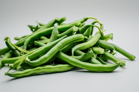 This realistic photo shows fresh green beans against a white, flat-colored background. The front view captures the vibrant green color and crisp texture of the beans, making it an ideal image for culinary websites, health and nutrition blogs, and grocery advertisingの素材