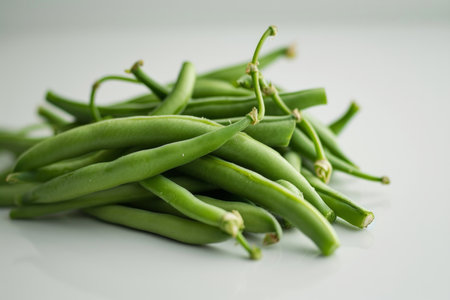 This realistic photo shows fresh green beans against a white, flat-colored background. The front view captures the vibrant green color and crisp texture of the beans, making it an ideal image for culinary websites, health and nutrition blogs, and grocery advertisingの素材