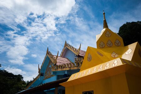 Top part of traditional Thai style Buddhist church with blue skyの写真素材