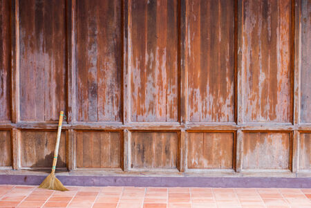Old wooden brown wall with a broom ready for cleaning workの写真素材
