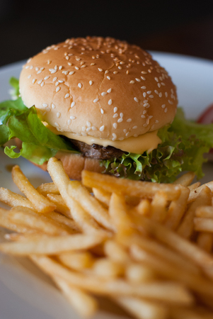 Cheeseburger And Fries with vegetables in white dish の写真素材