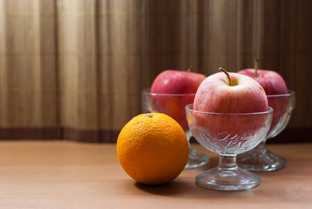 Apple in a glass of ice cream with Orange placed on a wooden tableの写真素材