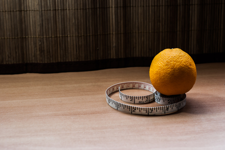 Fresh orange wrapped with measuring tape on the tableの写真素材
