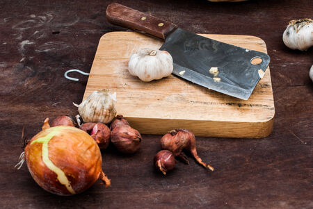 Shallots , Onion , Garlic , Chopping board and Knife on the table
