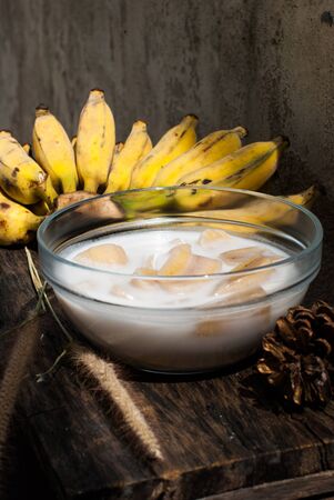 Banana in coconut milk put on wood table,Thai desertの写真素材