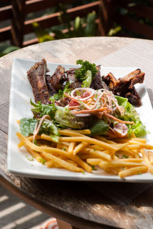 Pork spare ribs with salad and French Fries on the wooden tableの写真素材