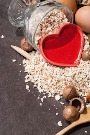 A Healthy Dry Oat meal with nut and Red heart in a wooden spoon on Black backgroundの写真素材