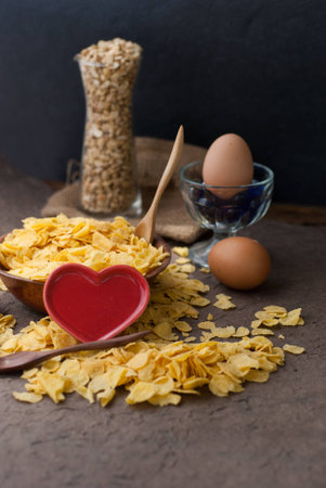 corn flakes in wooden bowl with spoons and Red heart on a tableの写真素材
