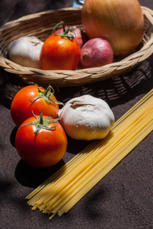 uncooked pasta and tomatoes , cartridge shells , garlic with Onions food closeupの写真素材