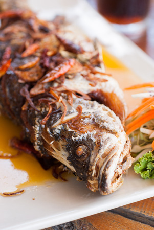 Fried fish with fresh herbs and sweet spicy sauce on plateの写真素材