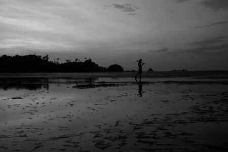 man on the beach with reflection in water during sunset.Thailandの写真素材