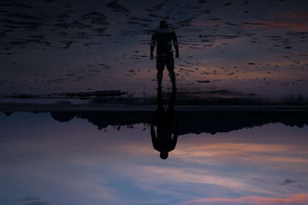 man on the beach with reflection in water during sunset.Thailandの写真素材