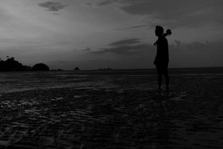 man on the beach with reflection in water during sunset.Thailandの写真素材