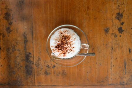 A cup of hot cappuccino and bread on wooden tableの写真素材