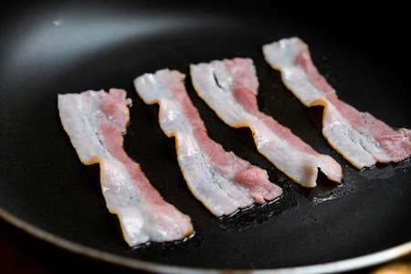 slices of fresh fried bacon in a pan for breakfast