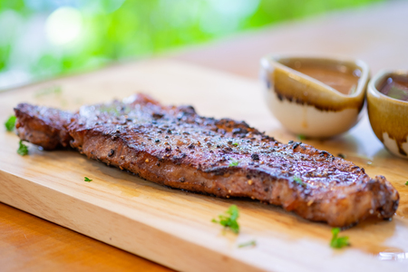 Steak Sirloin against with fries and sauce on a wooden tray