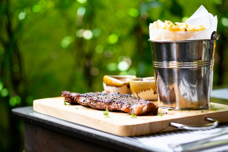Steak Sirloin against with fries and sauce on a wooden trayの写真素材
