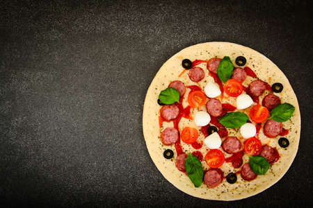 Raw Pepperoni Pizza with Sausage, Cheese, Mozzarella, Olives and Basil Studio Photoの写真素材