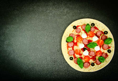 Raw Pepperoni Pizza with Sausage, Cheese, Mozzarella, Olives and Basil Studio Photoの写真素材