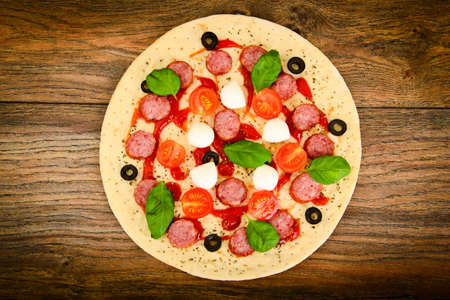 Raw Pepperoni Pizza with Sausage, Cheese, Mozzarella, Olives and Basil Studio Photoの写真素材