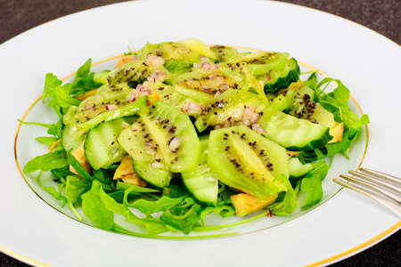 Arugula salad, kiwi and cucumber on white plate. Studio Photoの写真素材