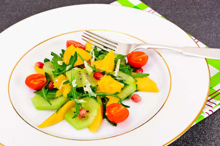 Fresh mango, arugula, kiwi, orange and pomegranate on White Plate. Studio Photoの写真素材